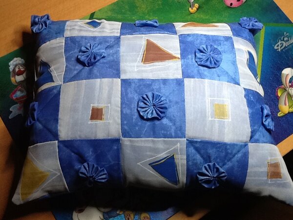 Das Kopfkissen habe ich aus einer alten blauen Tischdecke und einem Gardinenrest genäht. Auf die blauen Felder habe ich Stoffjojos genäht.