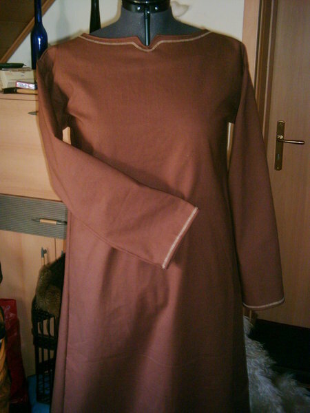 Unterkleid aus schokobrauner Baumwolle.
Am Halsausschnitt und Ärmelsaum schmale Stickerei in beige.
